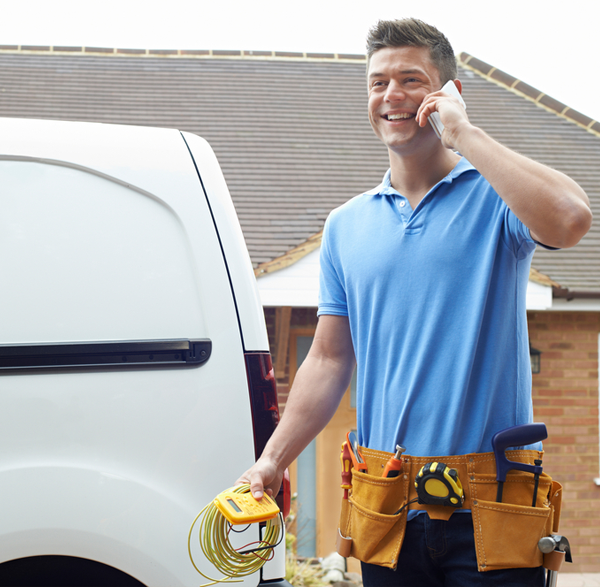 Photo of a smiling technician taking a phone call as he finishes a job